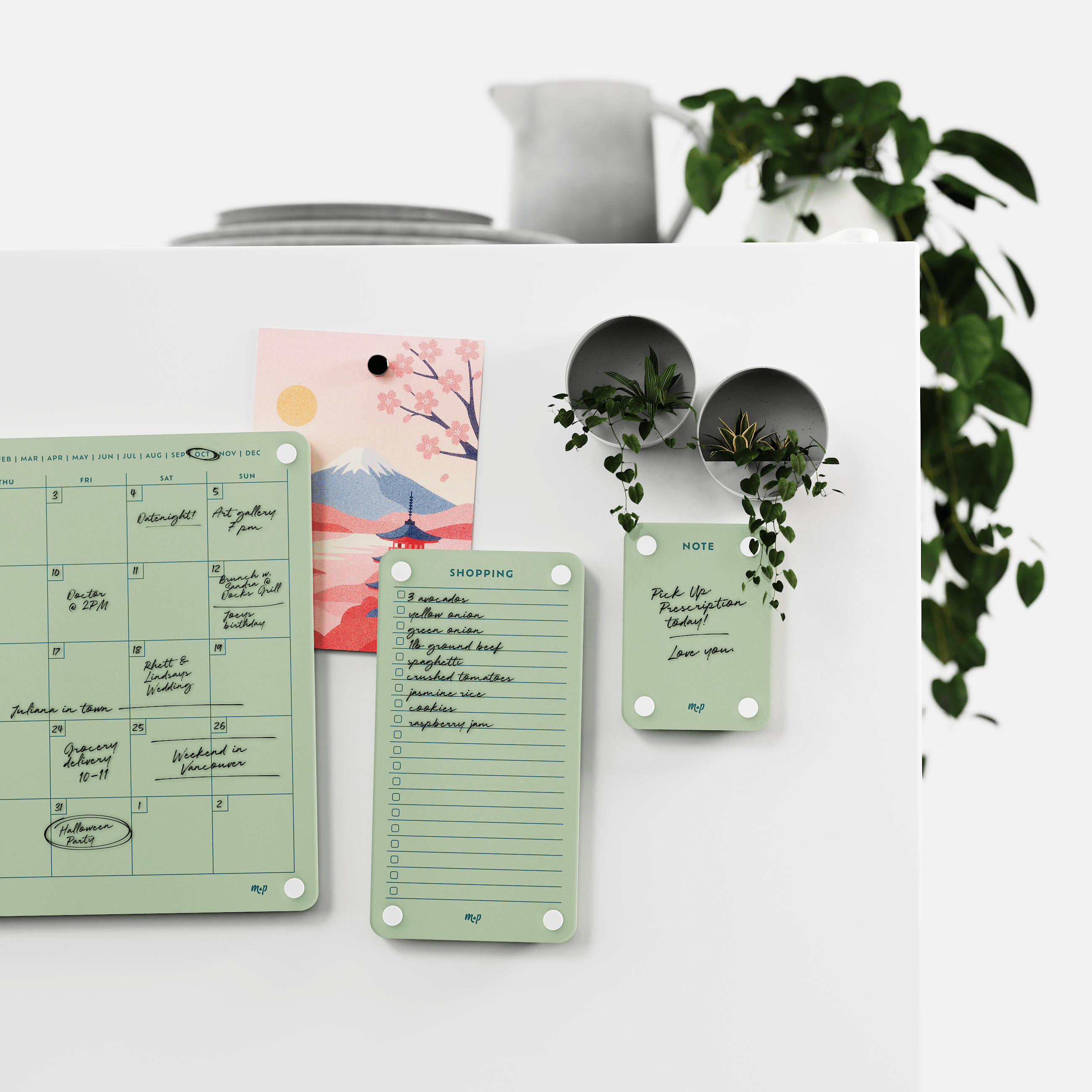 Matcha green monthly calendar, shopping list and note board on a white kitchen wall with magnetic planters